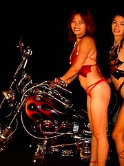 Two Asian biker babes pose nude in front of bikes